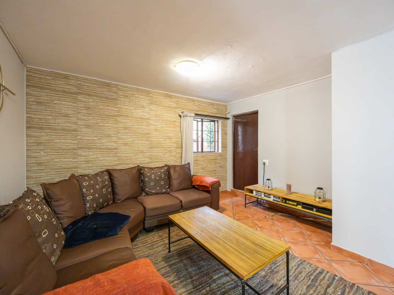 A living room featuring terracotta floor tiles and a textured feature wall, providing a functional and comfortable space.