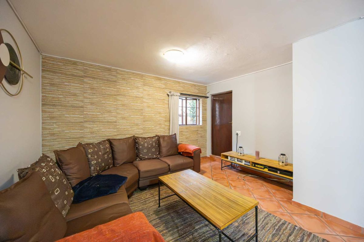 A living room featuring terracotta floor tiles and a textured feature wall, providing a functional and comfortable space.