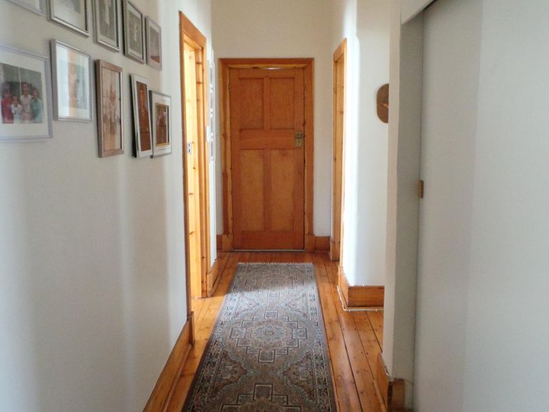 A bright hallway featuring polished timber flooring, classic timber door frames, and solid timber doors, providing a warm and traditional transition between rooms.