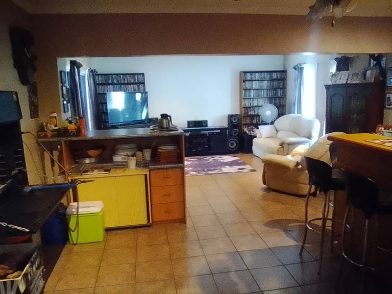 Open plan living area featuring tiled flooring and a built-in breakfast counter, providing a versatile space for dining and relaxation.