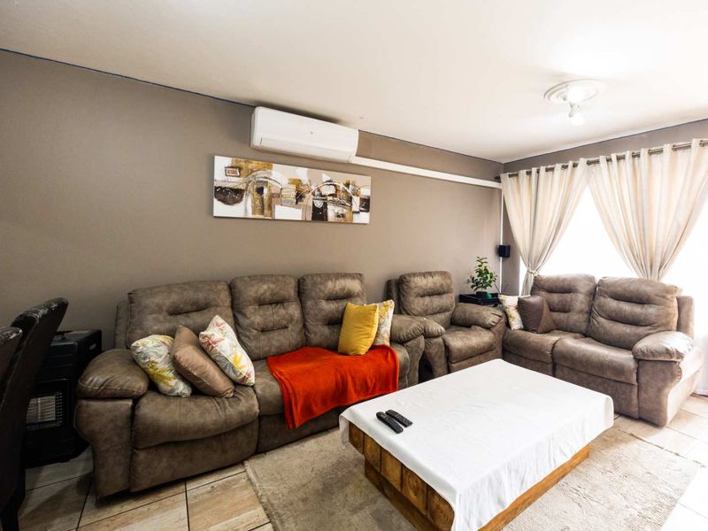 A comfortable living room featuring tiled flooring and a wall-mounted split-system air conditioning unit.