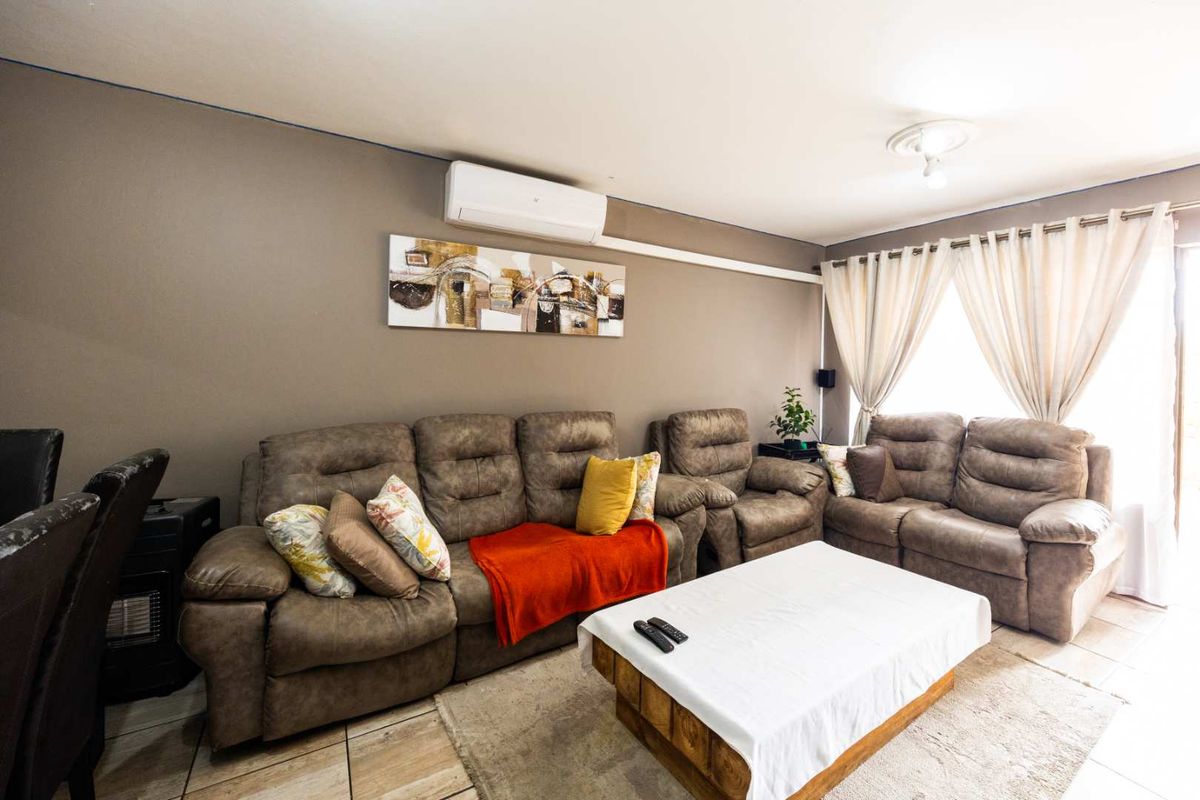 A comfortable living room featuring tiled flooring and a wall-mounted split-system air conditioning unit.