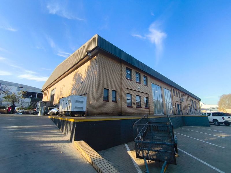 Industrial property featuring a brick facade, loading dock area, and paved driveway access, suitable for logistics or warehouse operations.