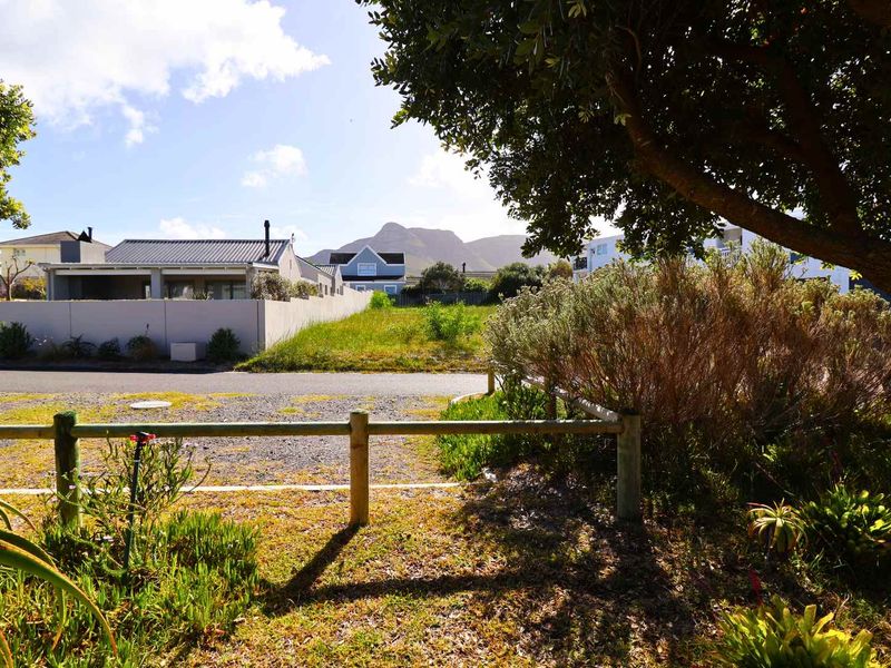 Street view of the vacant residential land featuring a timber fence, asphalt road frontage, and mountain views in the background.