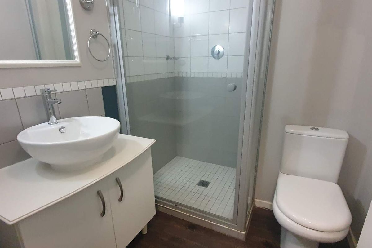 A compact bathroom featuring a modern vessel sink on a vanity cabinet, a glass-enclosed shower, and a standard toilet.
