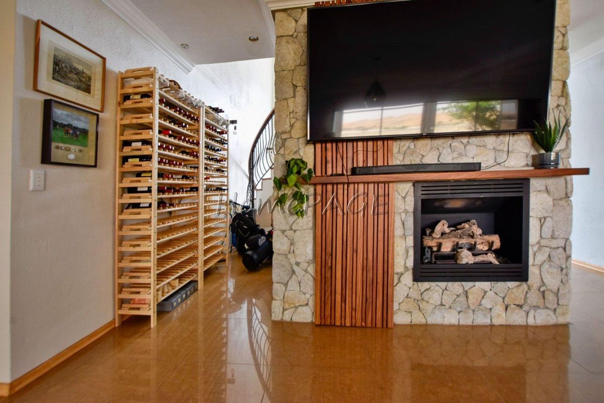 Living area featuring a stone-clad fireplace with timber slat detailing, polished tile flooring, and a built-in wine storage rack.