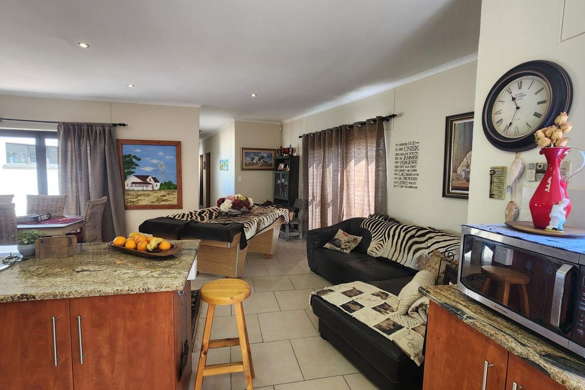 Spacious open-plan living area featuring tiled floors, granite kitchen countertops, and sliding doors providing access to the outdoor space.