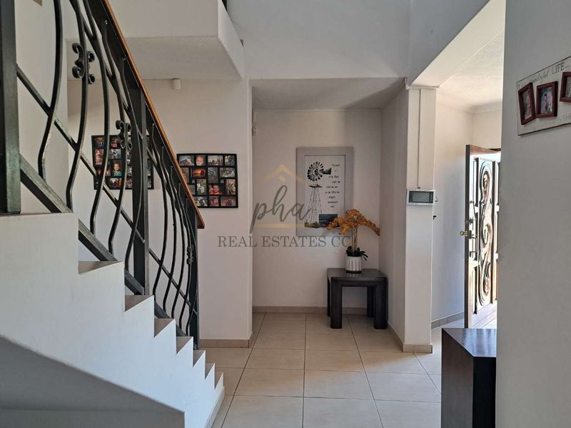 Welcoming entrance hall featuring tiled flooring and a decorative wrought iron staircase railing leading to the upper level.