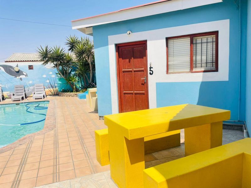 Outdoor pool area featuring a tiled patio, built-in concrete seating, and direct access to a unit with security bars on the window.