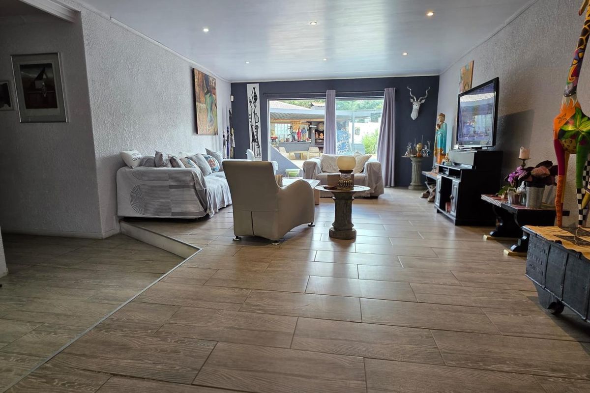 Spacious living area featuring wood-look tiled flooring, recessed ceiling lighting, and large sliding glass doors providing access to the outdoor patio space.