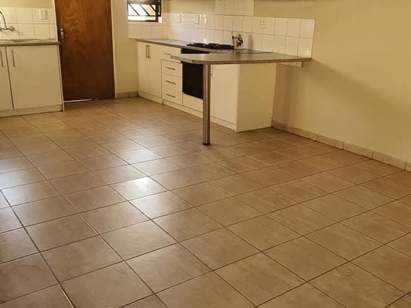 A functional kitchen featuring tiled flooring, built-in cabinetry, a tiled backsplash, and an integrated oven with an extractor fan.