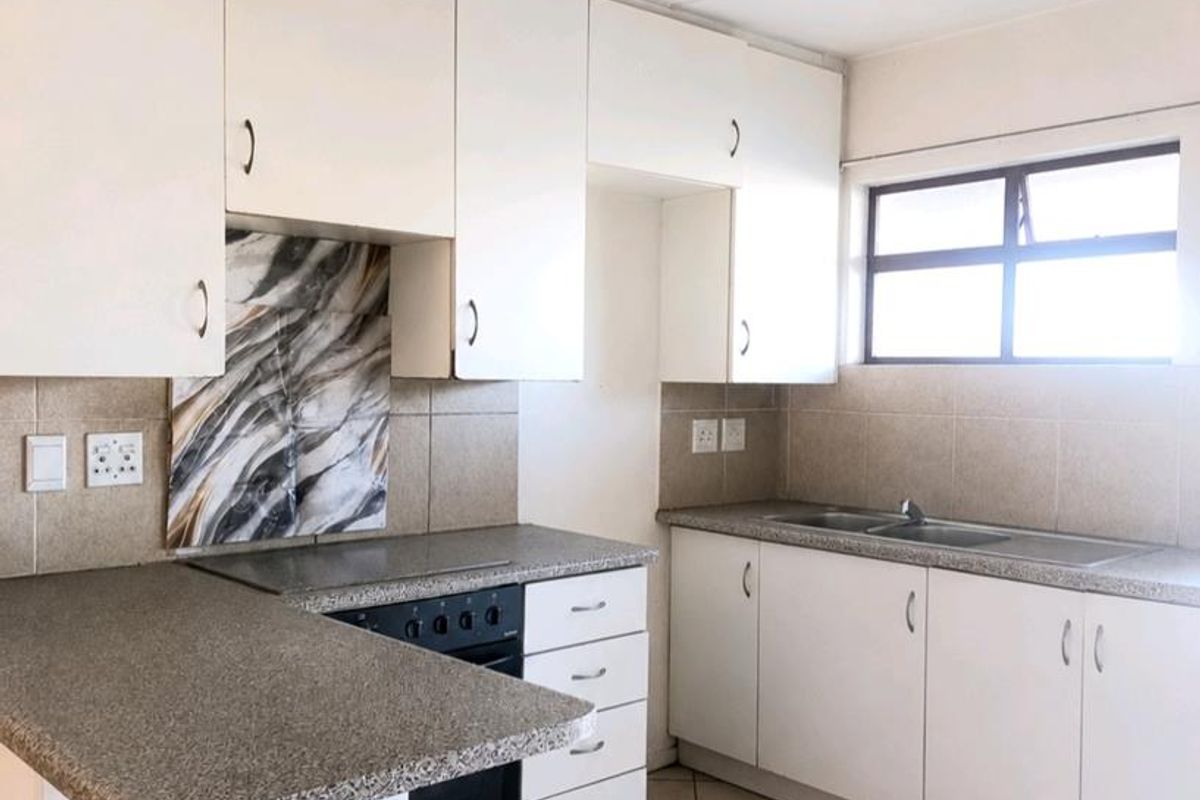 A functional kitchen featuring white cabinetry, granite-look laminate countertops, a built-in oven and hob, and neutral tiled flooring.