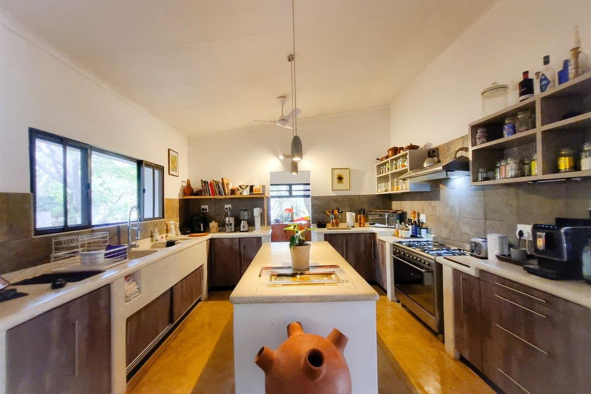Spacious kitchen featuring a central island, stone countertops, built-in gas stove, extractor fan, and ample cabinetry with integrated shelving.