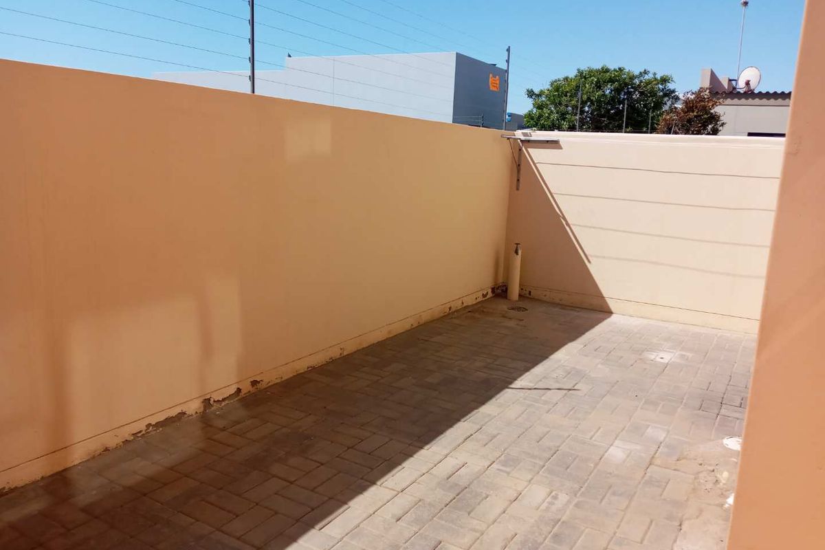 A private outdoor courtyard area featuring paved flooring and high boundary walls with electric fencing.