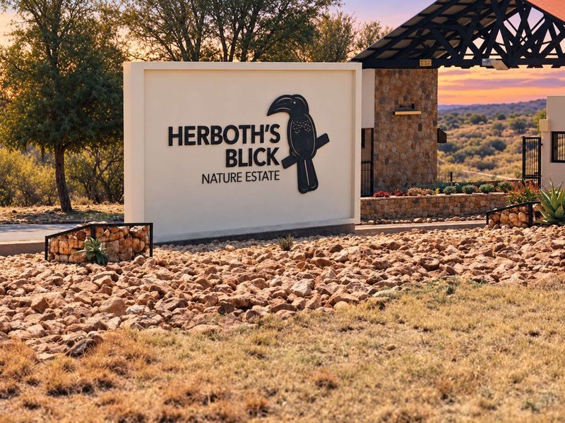 Entrance view of Herboth's Blick Nature Estate featuring stone masonry, professional signage, and landscaped rock garden elements.