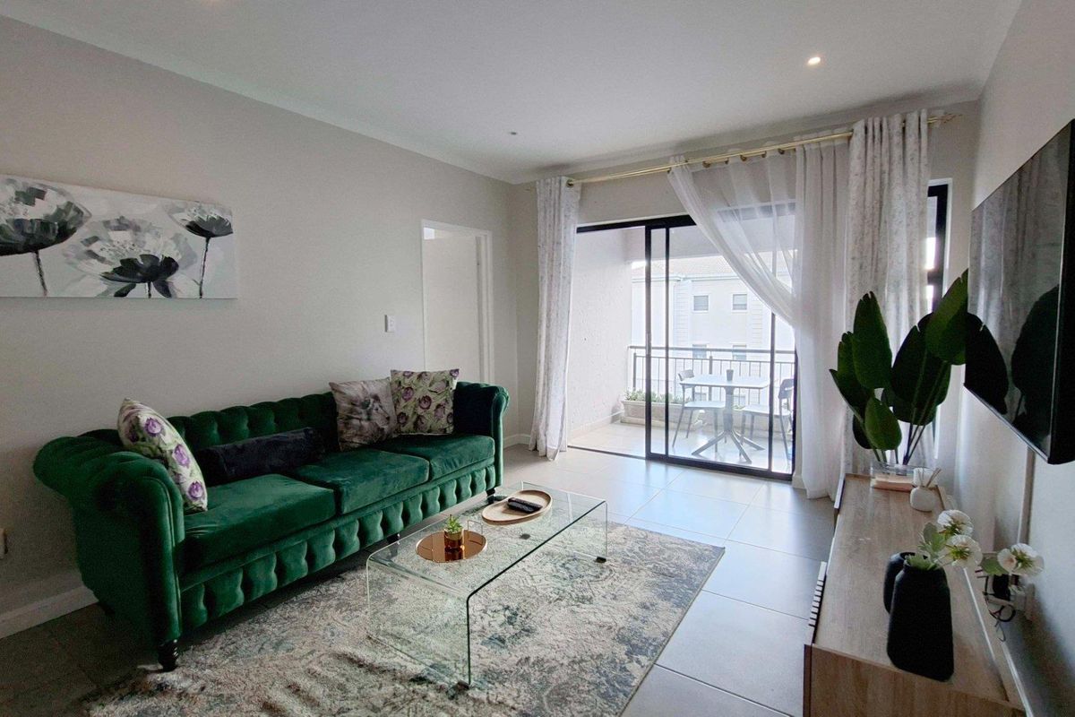 A bright and modern living room featuring tiled flooring, recessed lighting, and direct access to a private balcony through sliding glass doors.