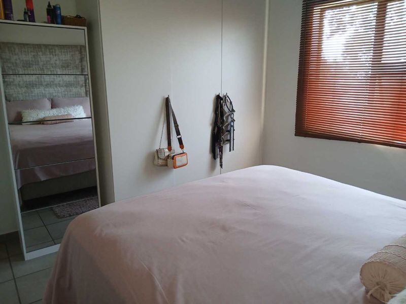 A bedroom featuring built-in cupboards and wooden venetian blinds, providing functional storage and adjustable natural light control.