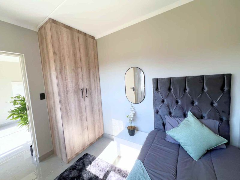 A well-maintained bedroom featuring neutral wall tones, tiled flooring, and a functional built-in wardrobe with a wood-grain finish.