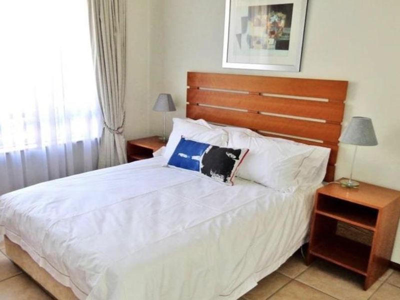 A functional bedroom featuring tiled flooring and neutral wall finishes, providing a comfortable and well-lit sleeping space.