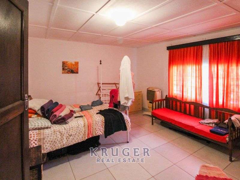 A bedroom featuring tiled flooring and a panelled ceiling, offering a functional space with natural light from the window.