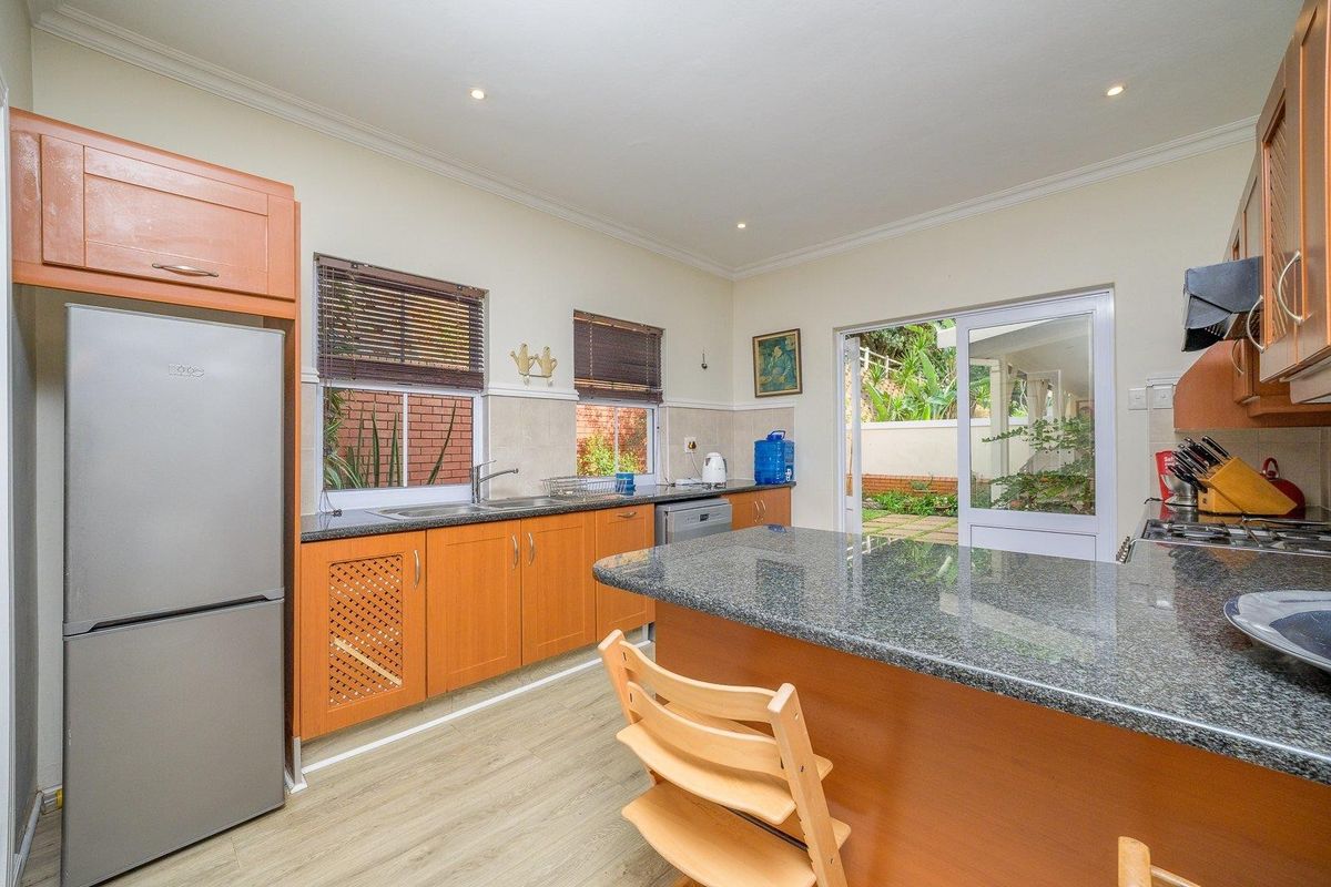 Functional kitchen featuring granite countertops, wooden cabinetry, and a gas hob, with direct access to the rear patio through a sliding glass door.