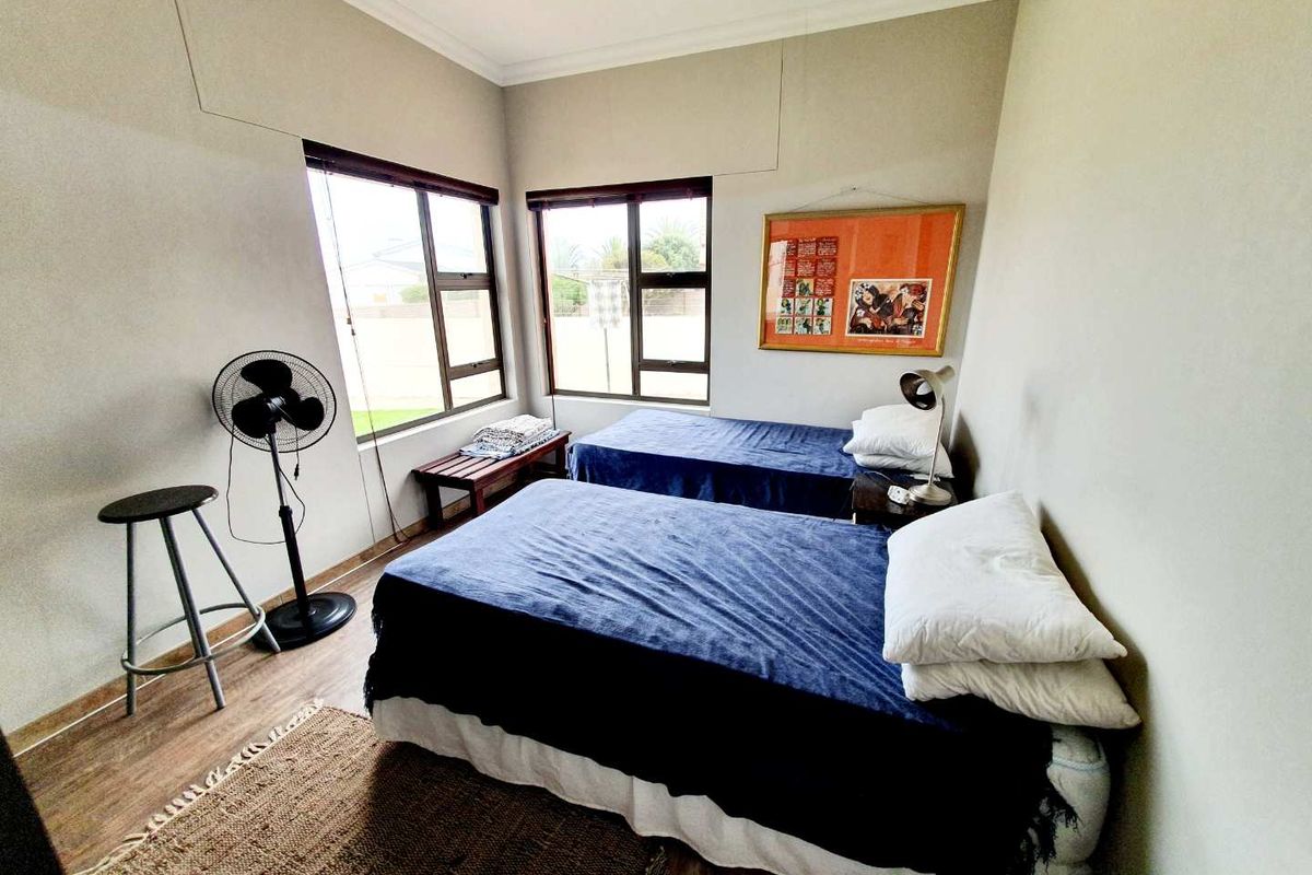 A bedroom featuring large windows, wood-look flooring, and neutral wall finishes.