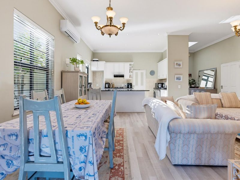 Spacious open-plan living and dining area featuring light laminate flooring, recessed lighting, and a functional kitchen with built-in cabinetry and appliances.