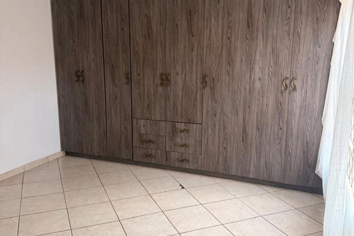 A bedroom featuring extensive built-in wooden cabinetry with integrated drawers and tiled flooring.