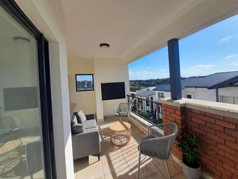 A covered balcony featuring tiled flooring, a built-in braai, and a brick and metal balustrade with views of the surrounding neighborhood.