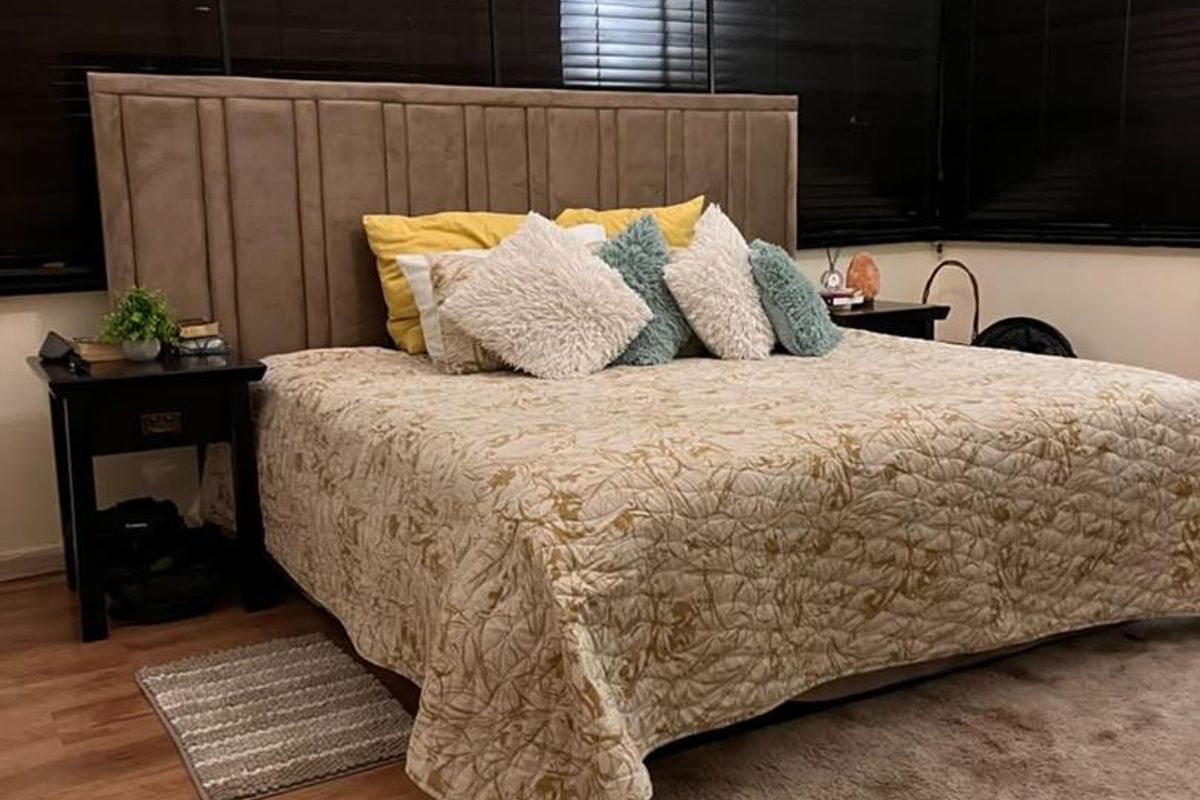 A spacious bedroom featuring wood-look flooring, dark venetian blinds, and a neutral color palette.