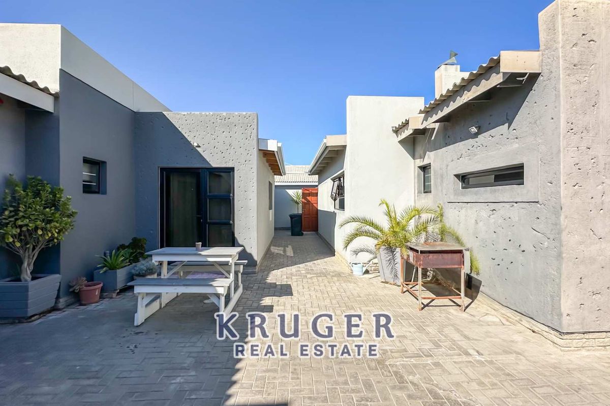 A paved rear courtyard area between building wings, featuring textured exterior walls and access to the property's rear entrance.