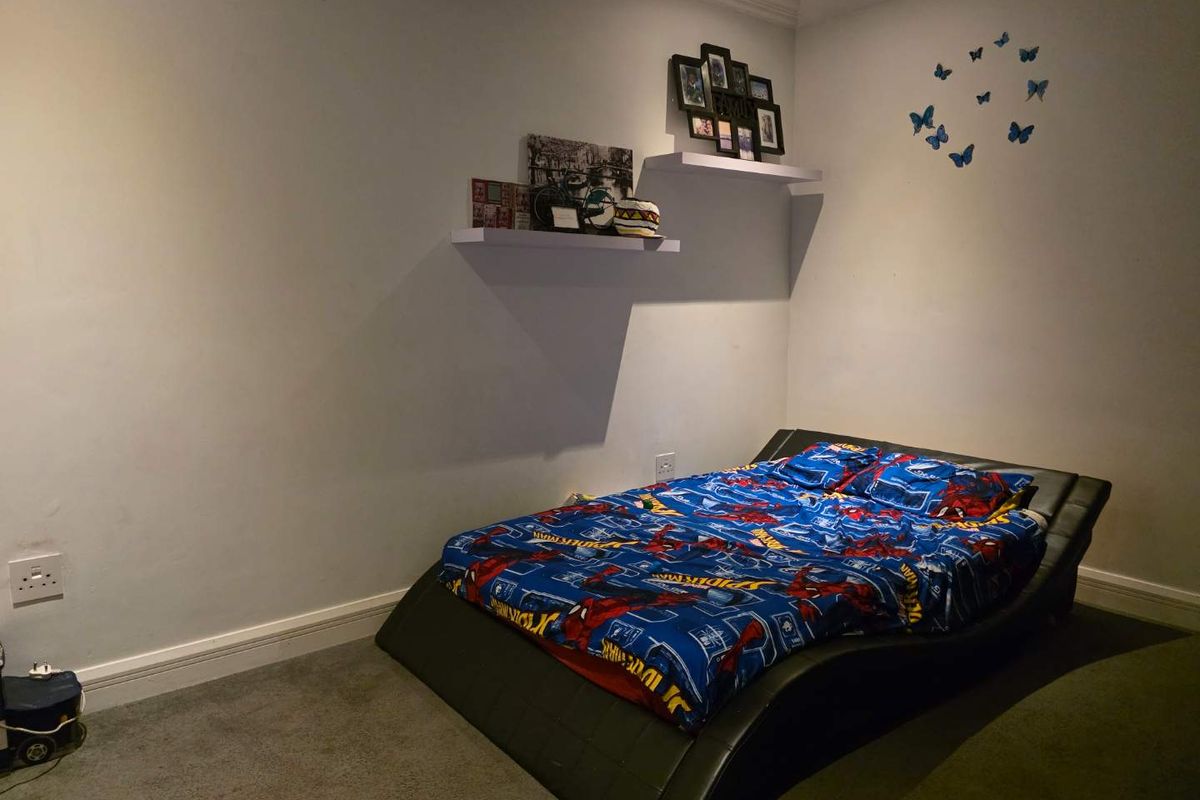 A bedroom featuring neutral walls, carpeted flooring, and two wall-mounted floating shelves.