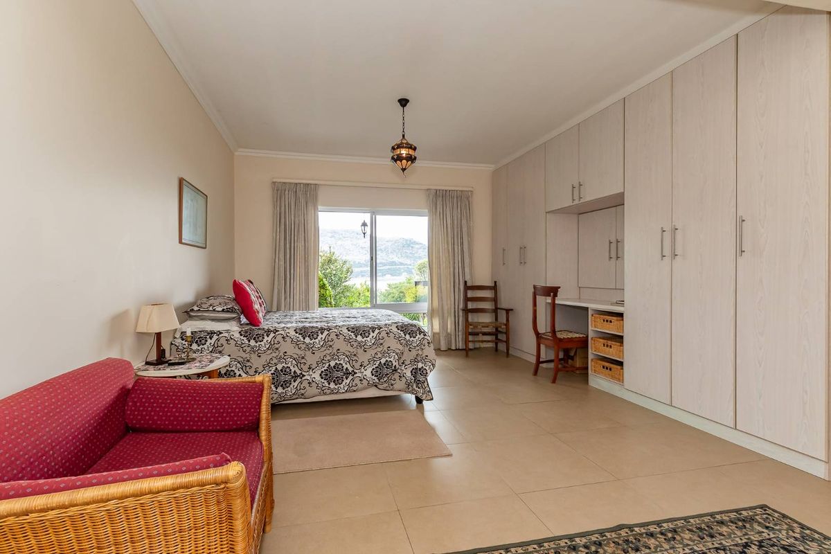 Spacious bedroom featuring extensive built-in cabinetry with integrated desk space, tiled flooring, and large window providing natural light and scenic views.