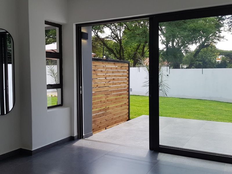Bright living area featuring large sliding glass doors that open onto a private patio and garden space with modern tiled flooring.