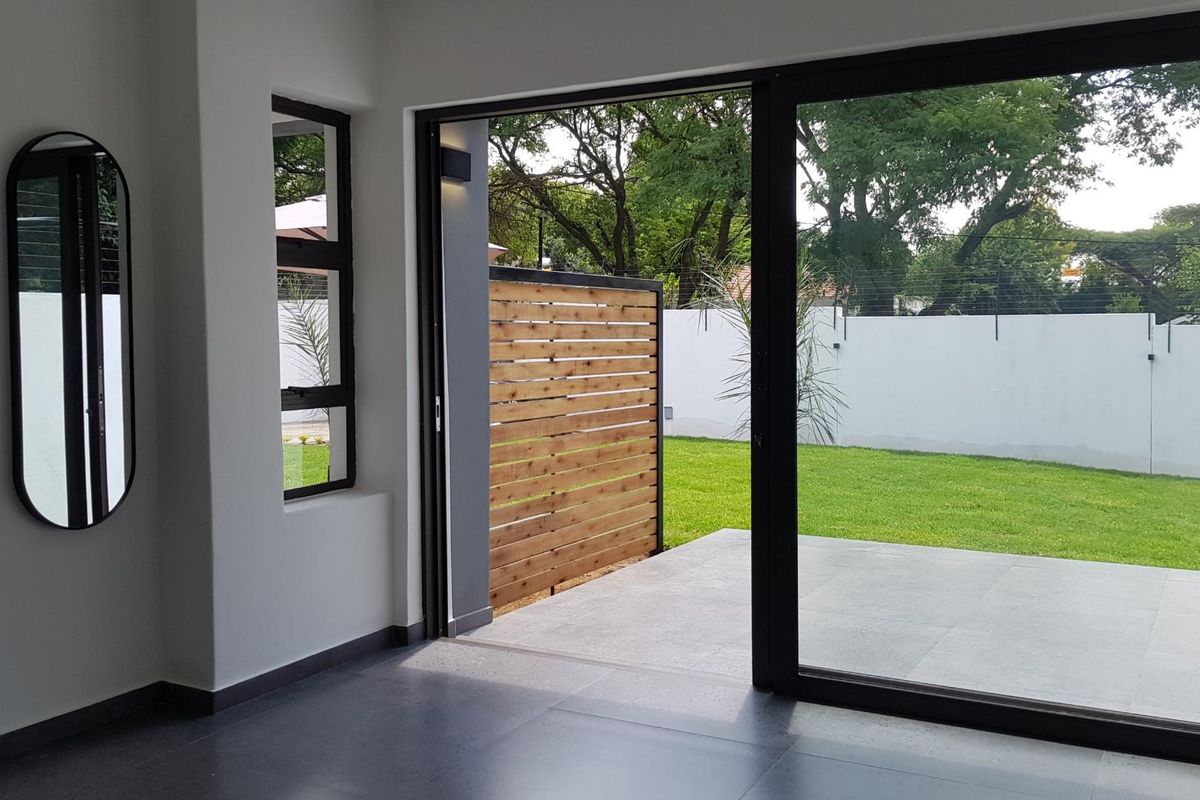 Bright living area featuring large sliding glass doors that open onto a private patio and garden space with modern tiled flooring.