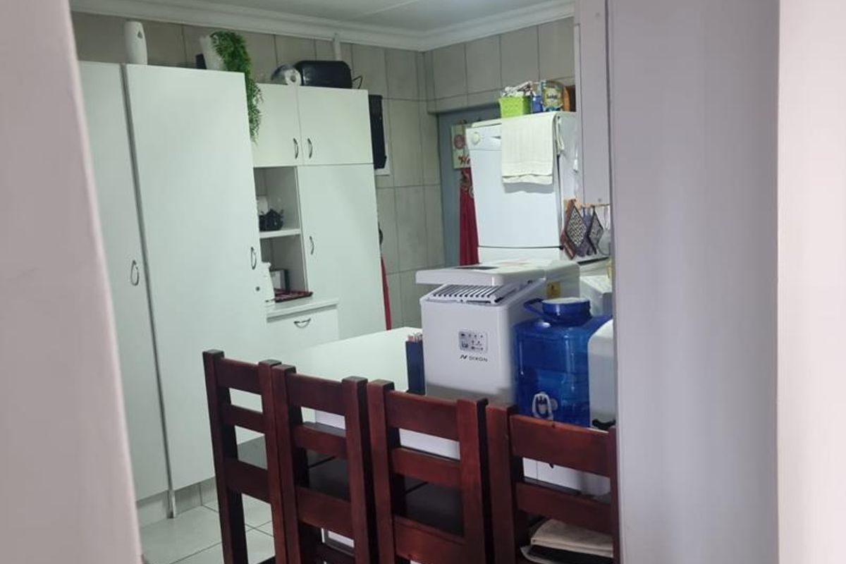A functional kitchen area featuring built-in white cabinetry and tiled flooring, viewed through a doorway.