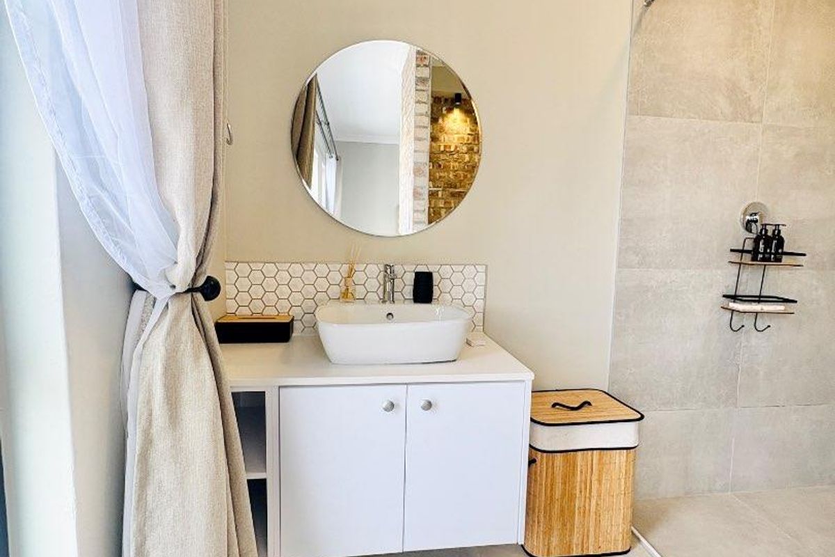 Modern bathroom featuring a vessel sink vanity, hexagonal tile backsplash, and a spacious walk-in shower with large format neutral tiling.