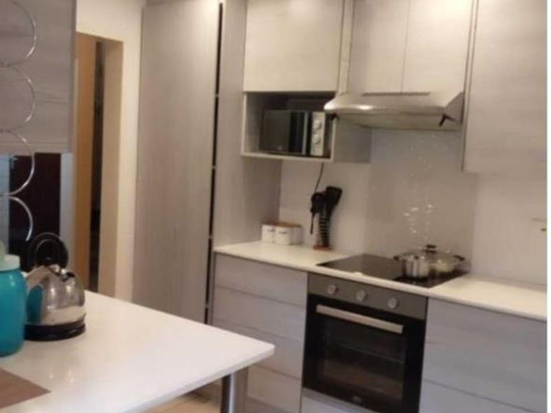 Modern kitchen featuring light wood-grain cabinetry, integrated appliances including an oven and hob, and sleek tiled flooring with recessed lighting.