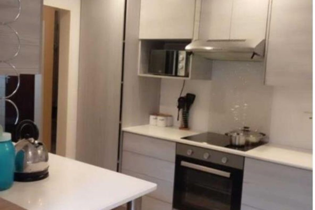Modern kitchen featuring light wood-grain cabinetry, integrated appliances including an oven and hob, and sleek tiled flooring with recessed lighting.