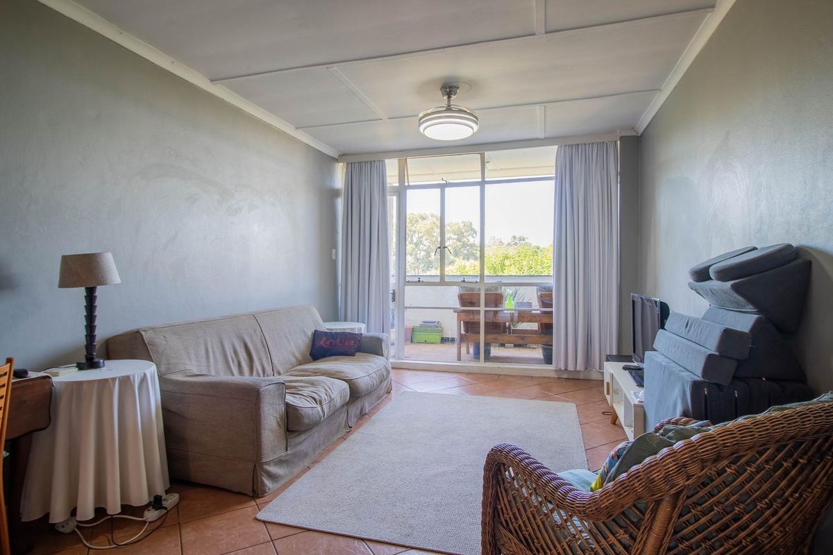 A living room featuring tiled flooring, a ceiling fan, and a sliding glass door providing access to an outdoor balcony area.