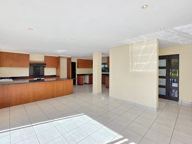 Spacious open-plan kitchen and living area featuring modern cabinetry, granite countertops, tiled flooring, and recessed lighting, offering a bright and versatile living space.