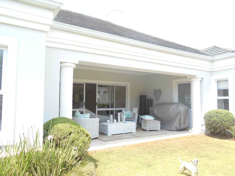 A covered patio area featuring tiled flooring and structural columns, providing direct access to the interior through sliding glass doors.
