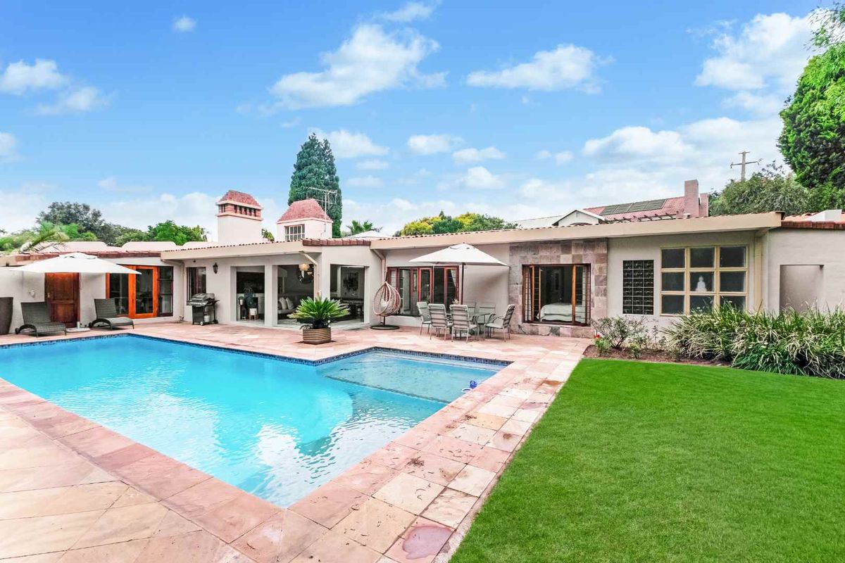 Spacious rear exterior featuring a swimming pool, paved patio area, and well-maintained lawn, providing an ideal space for outdoor entertaining.