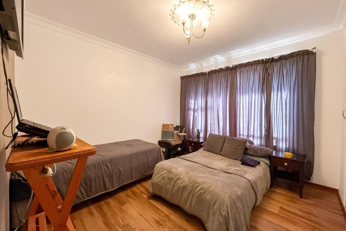 A bedroom featuring laminate flooring, decorative coving, and a central ceiling light fixture.