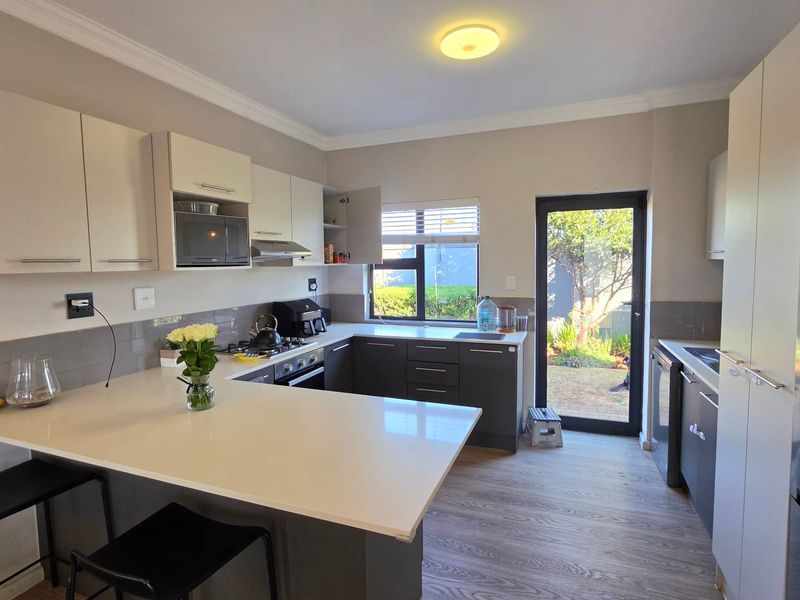 Modern kitchen featuring two-tone cabinetry, quartz countertops, gas hob, and direct access to the rear garden area.