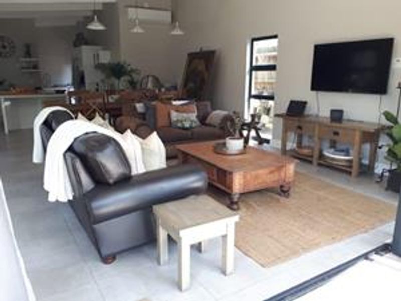 Spacious open-plan living area featuring tiled flooring, modern pendant lighting, and a split-system air conditioner, seamlessly connecting to the kitchen and dining space.