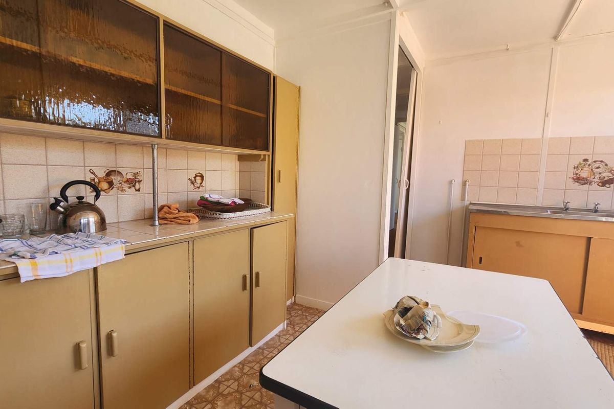 A dated kitchen featuring original cabinetry, tiled splashbacks, and a functional layout, offering significant potential for a modern renovation.