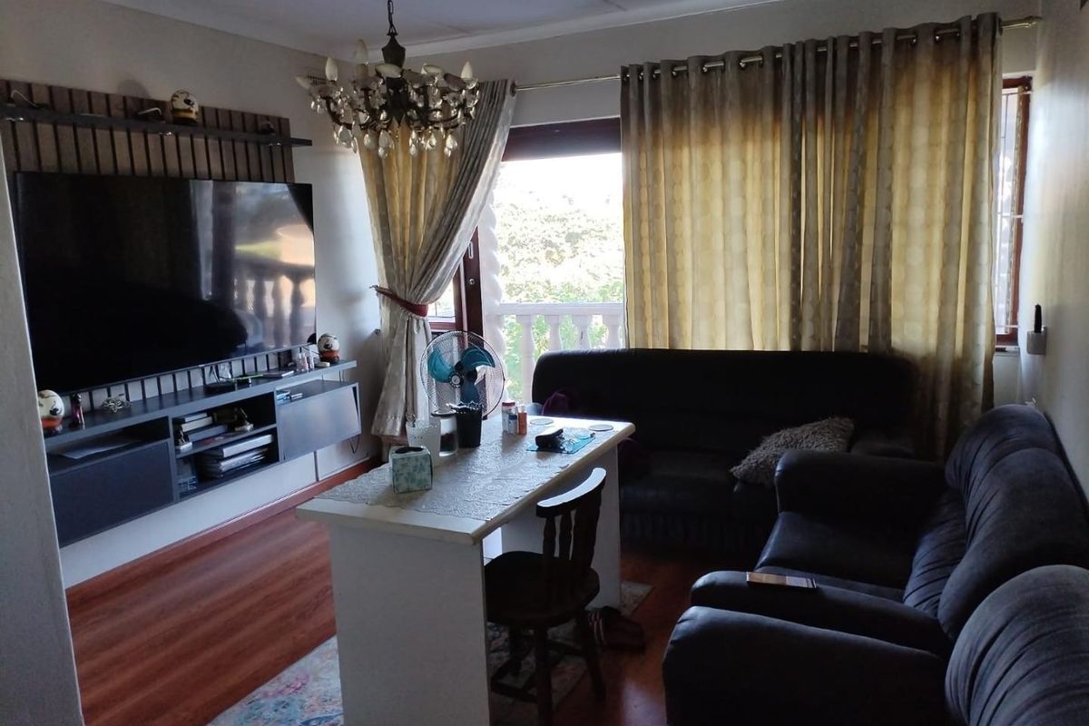 A cozy living room featuring laminate flooring, a built-in media console, and a decorative chandelier, with direct access to an outdoor balcony area.