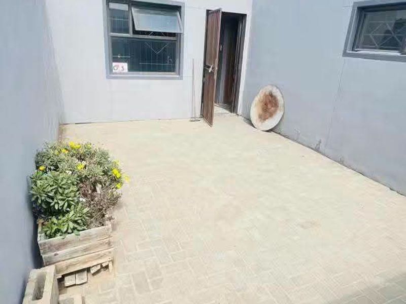 A private paved rear courtyard area featuring high boundary walls, security gate access, and external lighting.