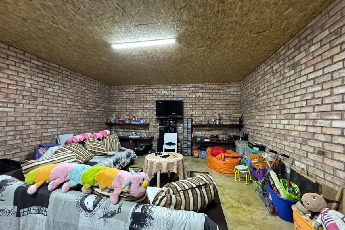A rustic living room featuring exposed face-brick walls and an OSB board ceiling, providing a casual, industrial-style space.